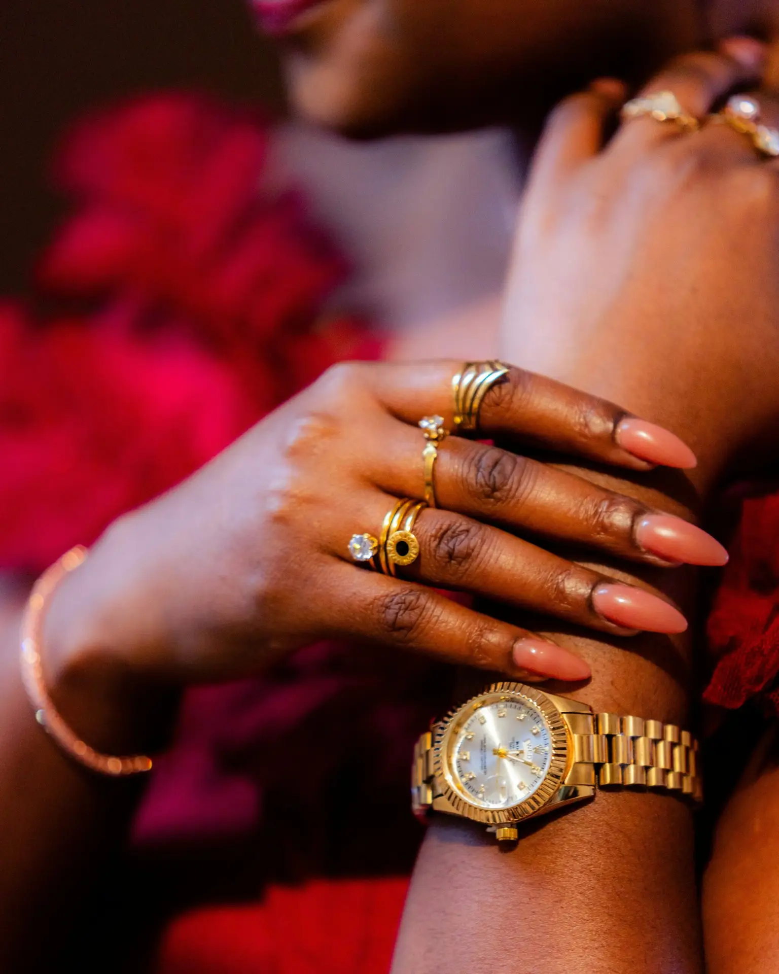 A hand showcases jewelry and a gold watch.